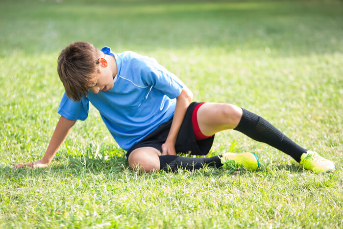 Student athlete resting in grass after injury.