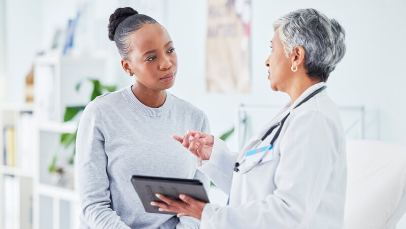Woman consulting with physician, both wearing white.