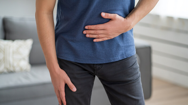 Man holding his hand over his stomach.